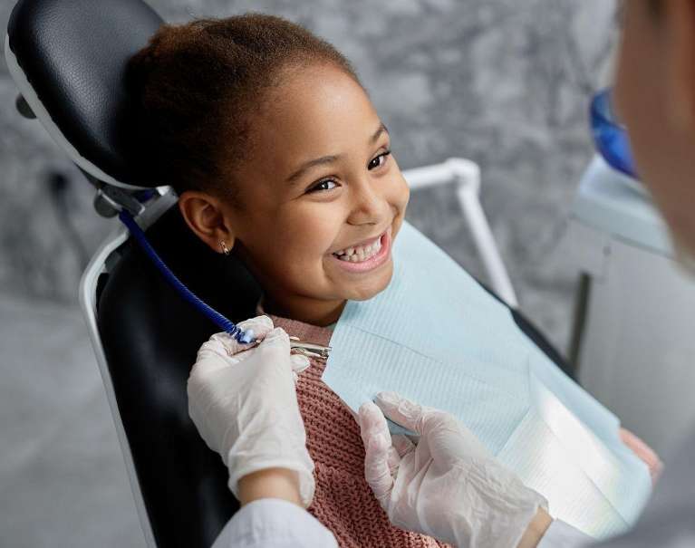 Child smiling brightly after a gentle dental extraction.